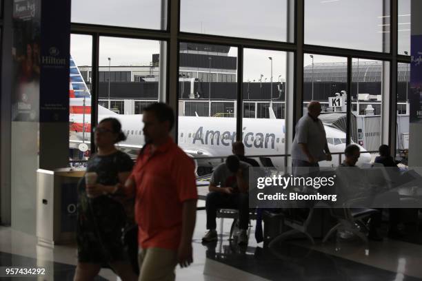 Travelers wait for flights as an American Airlines Group Inc. Plane sits during an event to mark the opening of five new gates inside Terminal 3 at...