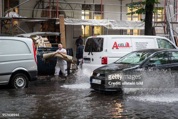 Deutschland Germany Berlin Szenen aus der Regenburger Str. Während heftiger Regenfälle. Handwerker arbeiten neben überfluteter Strasse.