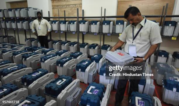 Polling staff check the Electronic Voting Machines inside the strong room before distributing them at the mustering centre in Kamlabai Girls High...