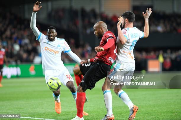 Guingamp's French forward Jimmy Briand vies with Marseille's French defender Boubacar Kamara and Marseille's French midfielder Morgan Sanson during...