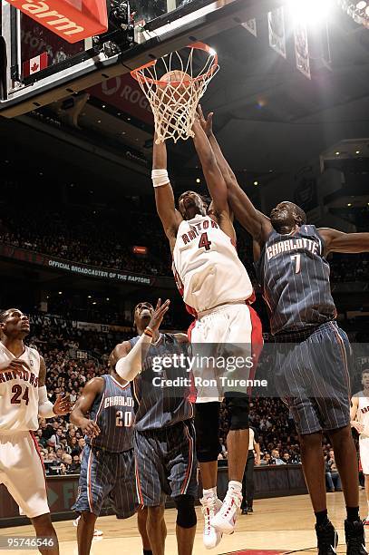 Chris Bosh of the Toronto Raptors puts up a shot between Gerald Wallace and DeSagana Diop of the Charlotte Bobcats during the game on December 30,...