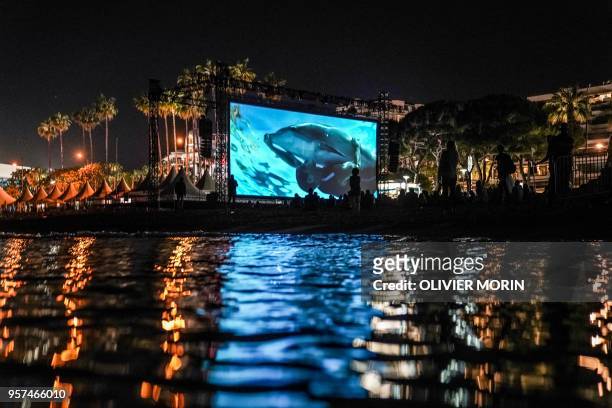 People watch late on May 11, 2018 the 30th anniversary screening of the film "Le Grand Bleu" at the Cinema de la Plage on the sidelines of the 71st...