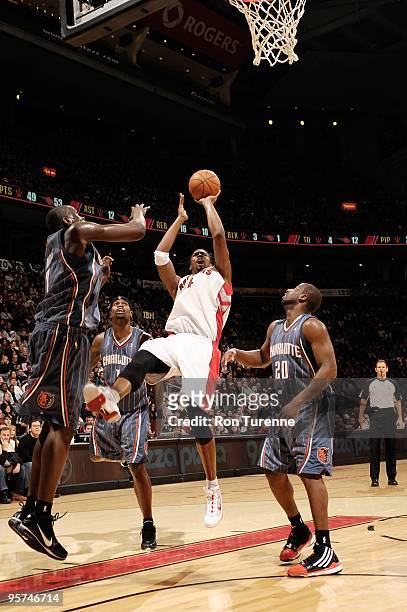 Chris Bosh of the Toronto Raptors puts up a shot against DeSagana Diop and Raymond Felton of the Charlotte Bobcats during the game on December 30,...