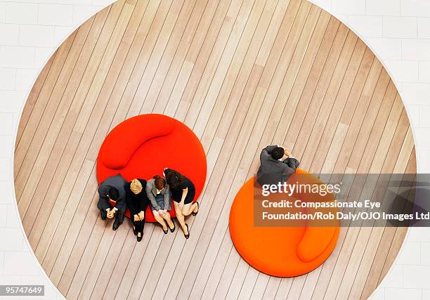 man sitting along away from group of people - preconceito imagens e fotografias de stock