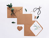 Kraft envelope card wedding invitation. Letter with olive branch over white background. Flat lay, top view