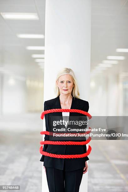 business woman tied to a pillar with red rope - frau gefesselt stock-fotos und bilder