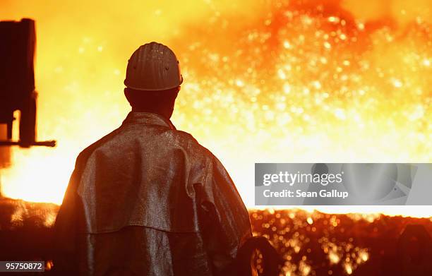 Worker watches as sparks fly from molten iron heated to approximately 1480 degrees Celsius flowing from a blast furnace at the ThyssenKrupp...