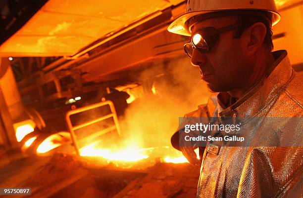 Worker wearing protective clothing stands near molten iron flowing from a blast furnace at the ThyssenKrupp steelworks on January 13, 2010 in...