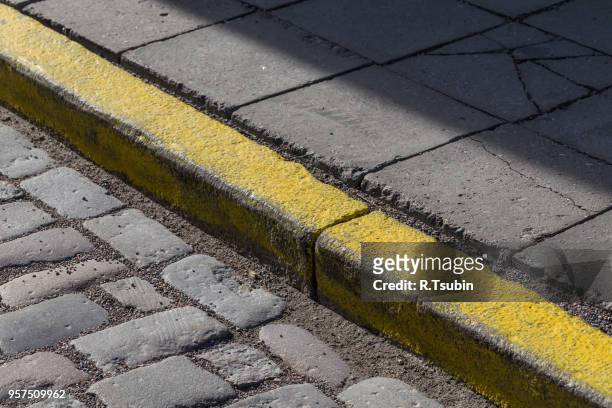yellow curb stone border in an old town road - kerb stock pictures, royalty-free photos & images