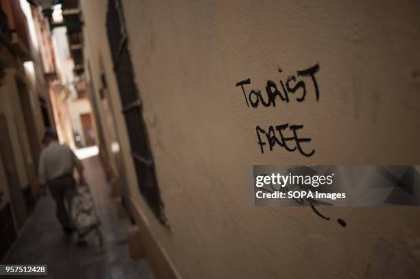 Graffiti painted on a wall with the words: "Tourist free zone" is seen as a man with a shopping cart walks along the street. During the last year,...