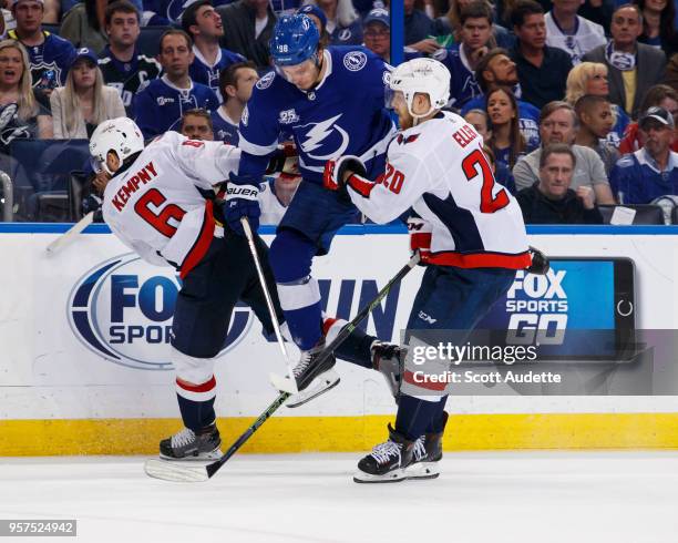 Mikhail Sergachev of the Tampa Bay Lightning leaps against Michal Kempny and Lars Eller of the Washington Capitals during Game One of the Eastern...