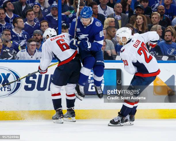 Mikhail Sergachev of the Tampa Bay Lightning leaps against Michal Kempny and Lars Eller of the Washington Capitals during Game One of the Eastern...