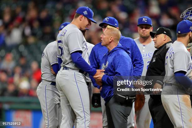 Kansas City Royals pitcher Brad Keller is examined by a trainer after being hit in the hand by a ball off the bat of Cleveland Indians third baseman...