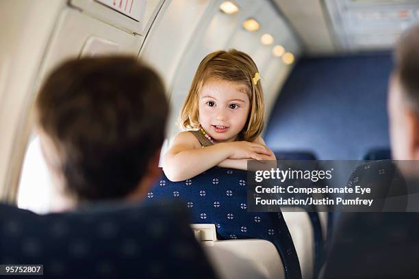 young girl leaning over seat talking to adults - kind flugzeug stock-fotos und bilder