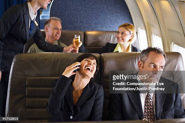business woman using cell phone on airplane - compassionate eye foundation imagens e fotografias de stock