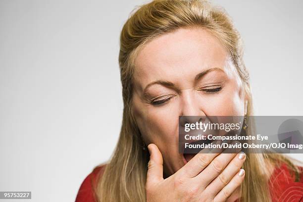 close up of yawning woman - mujeres de mediana edad fotografías e imágenes de stock