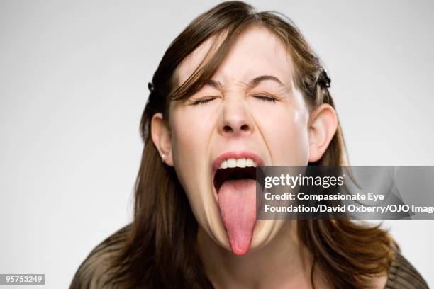 young woman sticking her tongue out - human tongue stock-fotos und bilder