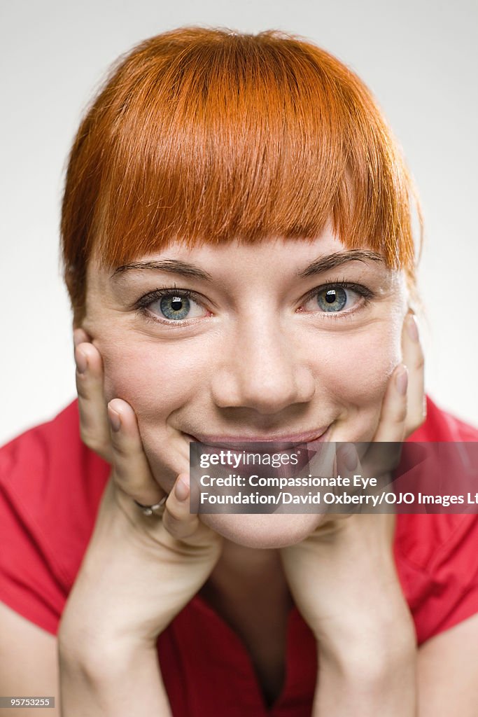 Portrait of red haired woman holding her face