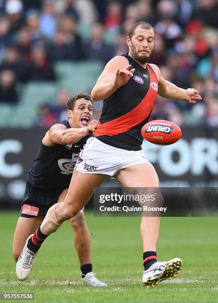 Tom Bellchambers of the Bombers kicks whilst being tackled by Ed Curnow of the Blues during the round eight AFL match between the Carlton Blues and...