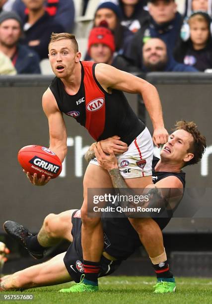 Devon Smith of the Bombers handballs whilst being tackled by Cameron O'Shea of the Blues during the round eight AFL match between the Carlton Blues...