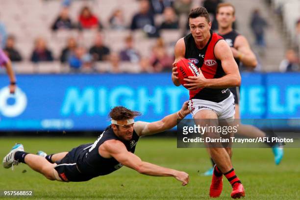 Conor McKenna of the Bombers evades Dale Thomas of the Blues during the round eight AFL match between the Carlton Blues and the Essendon Bombers at...