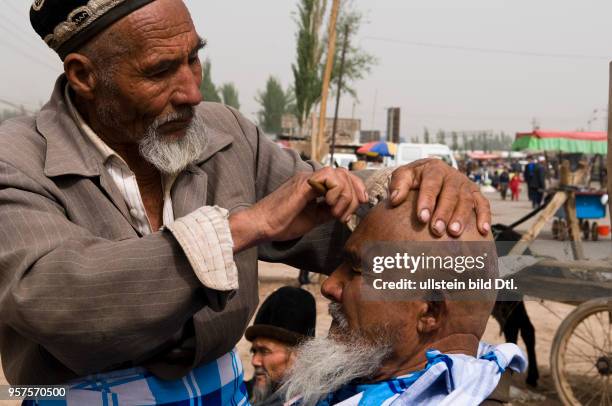China Xinjiang Kashgar - Sunday market; barber at work