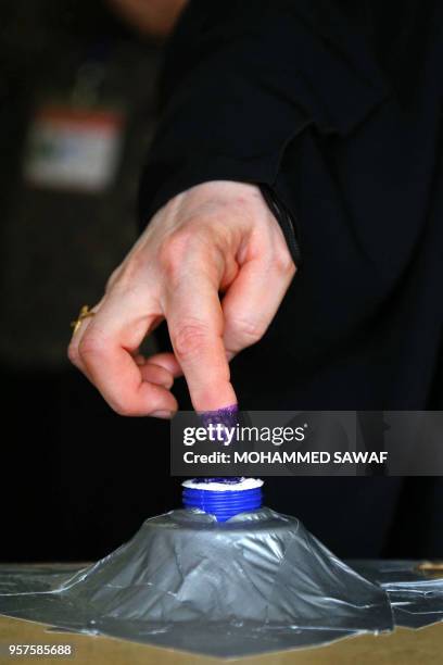 An Iraqi woman voter dips her index finger in ink at a poll station in the holy city of Karbala on May 12, 2018 as the country votes in the first...