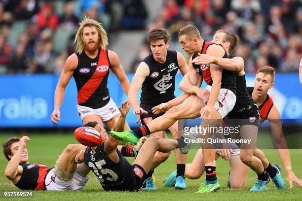 Devon Smith of the Bombers kicks whilst being tackled during the round eight AFL match between the Carlton Blues and the Essendon Bombers at...