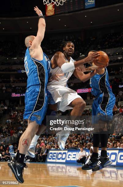 Nene of the Denver Nuggets puts up a shot between Marcin Gortat and Matt Barnes of the Orlando Magic during NBA action at Pepsi Center on January 13,...