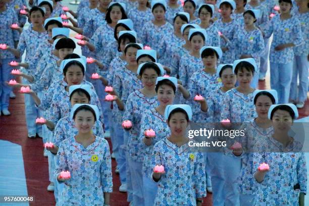 Nursing students hold candle lights to celebrate the 107th International Nurses Day at 37 Degree Dream Sea Park on May 10, 2018 in Yantai, Shandong...