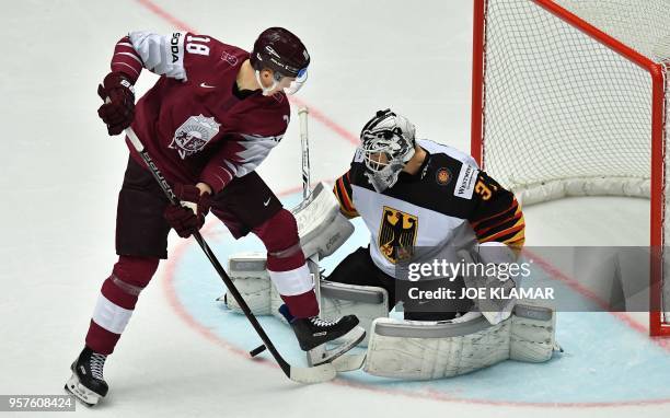 Latvia's Rodrigo Abols challenges for the puck with Germany's goalkeeper Niklas Treutle during the group B match Latvia vs Germany of the 2018 IIHF...