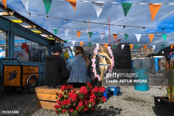People sit in front of a pro-choice mural relating to the laws regarding abortion in Dublin on May 11, 2018 ahead of the referendum. - Ireland will...