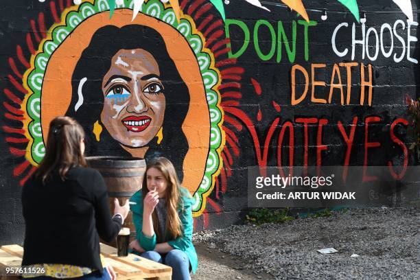 People talk over a drink in front of a pro-choice mural urging a yes vote in the referendum to repeal the eighth amendment of the Irish constitution,...