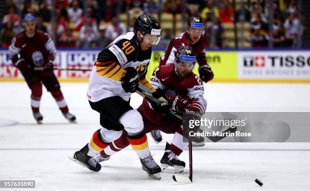 Mikelis Redlihs of Latvia and Bjoern Krupp of Germany battle for the puck during the 2018 IIHF Ice Hockey World Championship Group B game between...