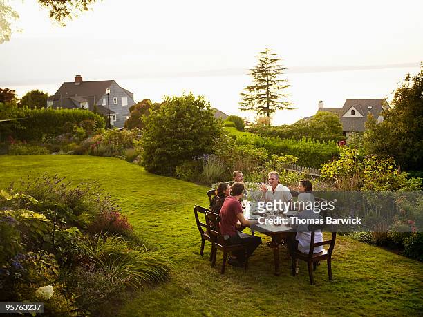friends sitting around outdoor dining table - dining overlooking water stock-fotos und bilder