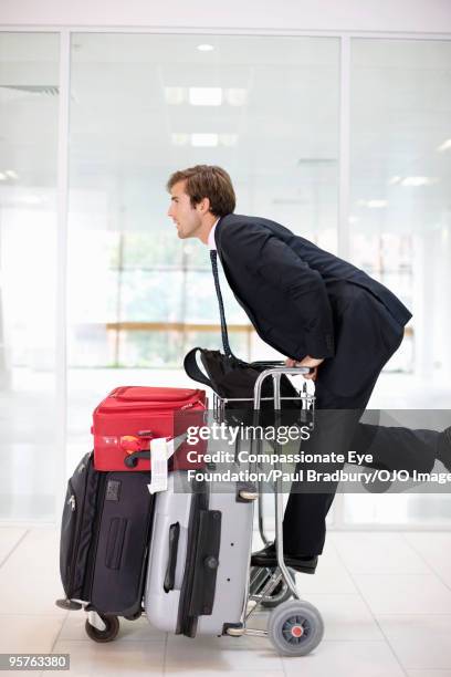 business man pushing luggage cart through airport - luggage trolley stock pictures, royalty-free photos & images