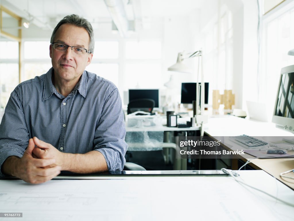Businessman sitting at drafting table in office