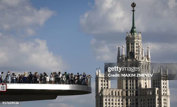 Tourists stand on the "Floating bridge" bridge in Zaryadye park in central Moscow on May 12, 2018.