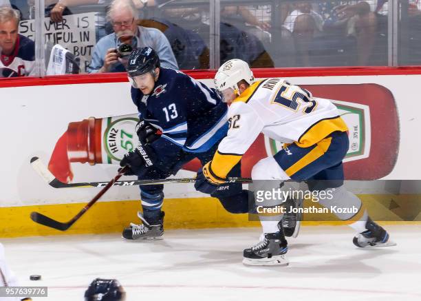 Brandon Tanev of the Winnipeg Jets and Matt Irwin of the Nashville Predators chase the loose puck along the boards during second period action in...