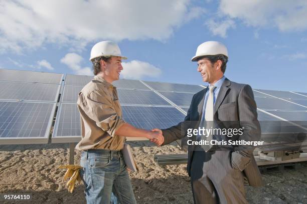 businessman shaking engineer's hand in solar plant - chris sattlberger stock pictures, royalty-free photos & images