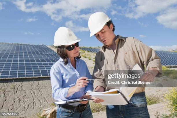 engineers looking at plans in solar plant - chris sattlberger stock pictures, royalty-free photos & images