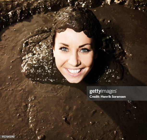 young woman smiling from mud bath - schlammbaden stock-fotos und bilder