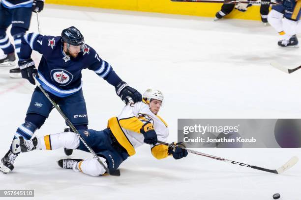 Kevin Fiala of the Nashville Predators falls to the ice as he and Ben Chiarot of the Winnipeg Jets chase the loose puck during second period action...