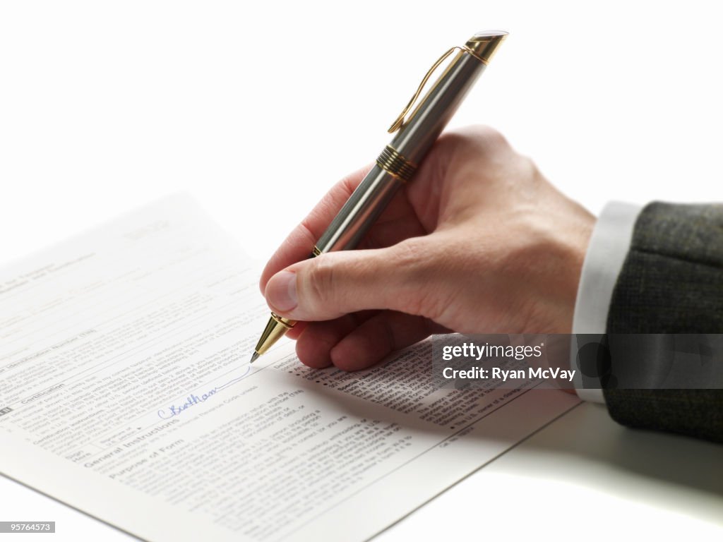 Hand with pen signing a document