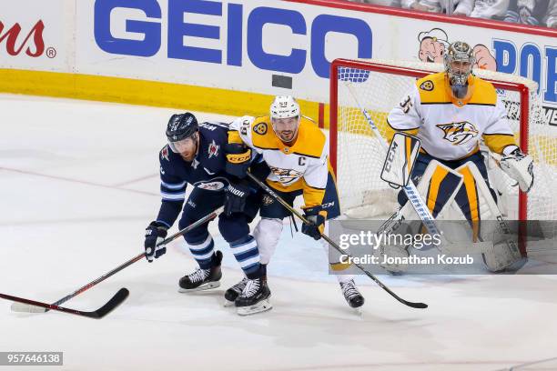 Blake Wheeler of the Winnipeg Jets battles Roman Josi of the Nashville Predators in front of goaltender Pekka Rinne as they keep an eye on the play...