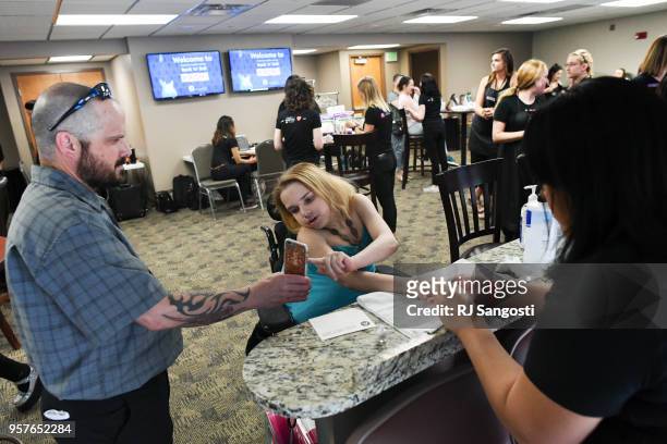 Jason Karroll holds his daughter's phone as she texts with her friend while getting her nails done before a special prom hosted for Childrens...
