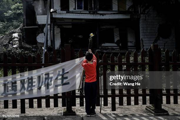 Boy lays flowers to mourn the victims at the ruins of earthquake-hit Beichuan county during the ten year anniversary on May 12, 2018 in Beichuan...