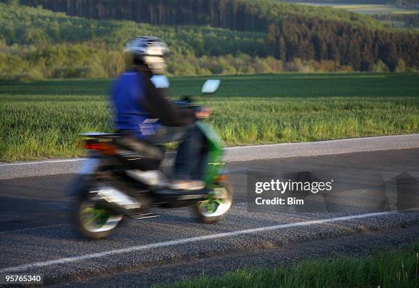teen riding home on his moped, motion blur - bromfiets stockfoto's en -beelden