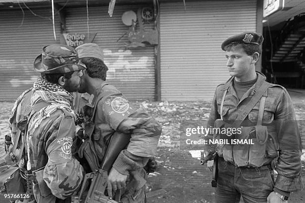 Shi'ite Amal Moslem militiaman kisses a Druze Socialist Progressive Party militiaman 20 February 1987 in west Beirut as a Syrian soldier looks on...
