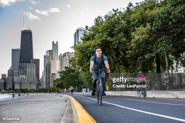 jeune homme vélo à chicago par le lac michigan, au transport au travail - chicago illinois photos et images de collection